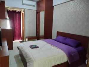 a bedroom with a large bed with a purple blanket at Japlen Room in Pondokcabe Hilir