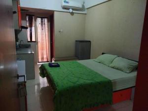 a bedroom with a bed with a green blanket on it at Japlen Room in Pondokcabe Hilir +20 photos