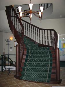 Una escalera con una alfombra verde. en Gutshaus Redewisch Hotel & Restaurant en Boltenhagen