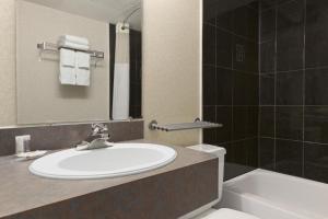 a bathroom with a sink and a toilet and a mirror at Days Inn by Wyndham Bridgewater Conference Center in Bridgewater