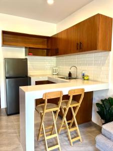 a kitchen with two bar stools and a refrigerator at Lunara Villas in El Nido