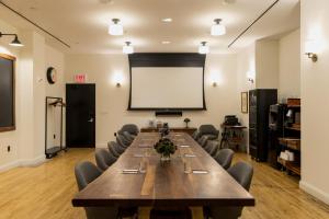 ニューヨークにあるエース ホテル ニューヨークの大きなテーブルと白いスクリーンが備わる会議室を利用できます。