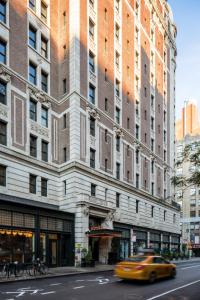 a yellow taxi cab driving past a tall building at Ace Hotel New York in New York
