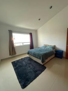 a bedroom with a bed with a rug and a window at Alma Xoloitzcuintle in Hércules