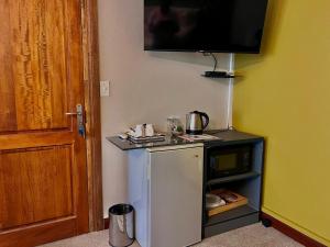 a small kitchen with a small refrigerator and a tv at Flamingo on Korsman in Benoni