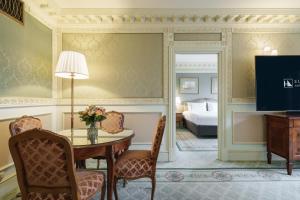 a room with a table and chairs and a bed at Eurostars Grand Hotel Wien in Vienna