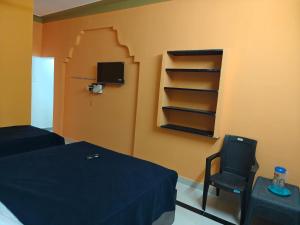 a bedroom with a bed and a chair and a tv at BNS Village Resort in Kolli Hills