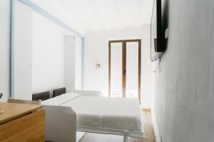 a white room with a bed and a tv on a wall at Godello - Harbor's Light in Villajoyosa