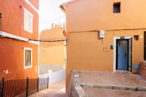 an orange building with a blue door in a alley at Godello - Harbor's Light in Villajoyosa