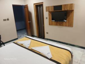 a bedroom with a bed with a tv on the wall at Hotel Vimas International in Madurai