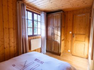 a bedroom with a bed and a window and wooden walls at Le Diable Bleu in Lamoura
