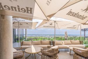 a patio with tables and chairs and umbrellas at Elegant AirConditioned Neria at Ellipse Waterfall in Midrand