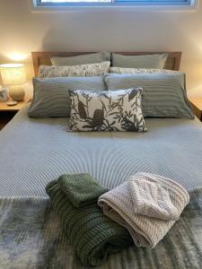 a bed with two blankets and pillows on it at Grevillea Cottage in Murrumbateman