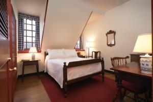 1 dormitorio con 1 cama, escritorio y 2 ventanas en Colonial Houses, an official Colonial Williamsburg Hotel, en Williamsburg