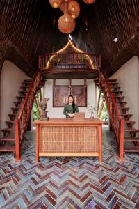 a woman sitting at a desk in a room with stairs at Lamia Bamboo Retreat Ninh Binh in Ninh Binh