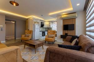 a living room with a couch and chairs and a kitchen at Avullar Palace Hotel in Antalya