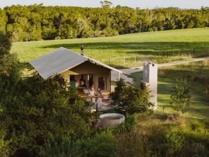 a cottage in a field with people sitting at a table at AfriCamps at Oakhurst in Wilderness
