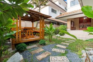 a wooden gazebo with a wooden table in a garden at The Phuket Pool Villa in Phuket