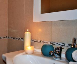eine Kerze auf einem Waschbecken mit Spiegel in der Unterkunft Casinha das Flores in Reguengos de Monsaraz + 17 Fotos