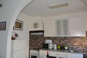 uma cozinha com armários brancos e um micro-ondas em Casinha das Flores em Reguengos de Monsaraz