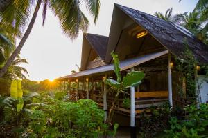 a house on the beach with the sun setting at Satya Boutique Resort & Spa in Havelock Island