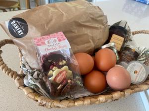 a basket filled with eggs and a bag of groceries at Grevillea Cottage in Murrumbateman