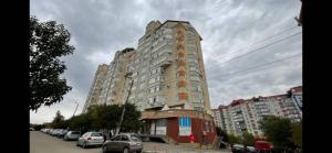 a tall building with cars parked in a parking lot at Ciocana in Chişinău