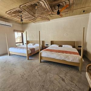 two beds in a room with a ceiling at Aaryavan, A boutique resort in Mount Ābu