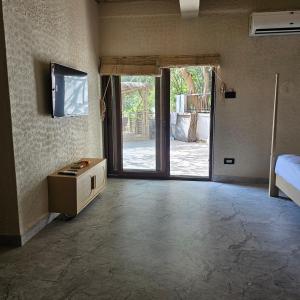 a room with a television and a room with a bed at Aaryavan, A boutique resort in Mount Ābu