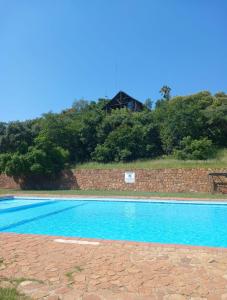 a blue swimming pool with a house in the background at Picturesque 82 in Buffelspoort +21 photos