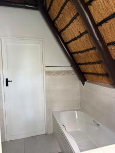 a white bath tub in a bathroom with a wooden ceiling at Picturesque 82 in Buffelspoort