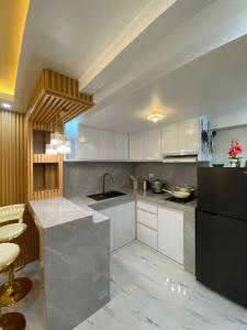 a kitchen with white cabinets and a black refrigerator at Urban Haven- Naga City in Naga