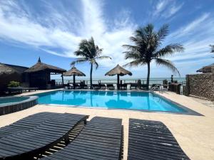 a swimming pool with palm trees and the ocean at Viva Beach Resort Mui Ne in Mui Ne +18 photos