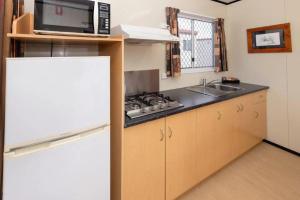 a kitchen with a stove and a microwave and a refrigerator at BIG4 Opal Holiday Park in Lightning Ridge