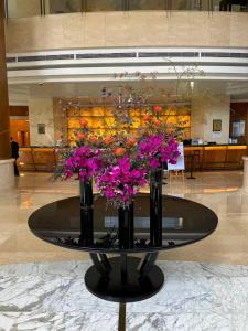 a table with two vases with purple flowers on it at Ramada Plaza Pudong Shanghai in Shanghai