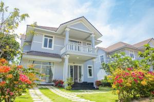 a white house with flowers in the yard at Căn Hộ OceanVista & Biệt Thự Sealink Phan Thiết - Mũi Né in Phan Thiet