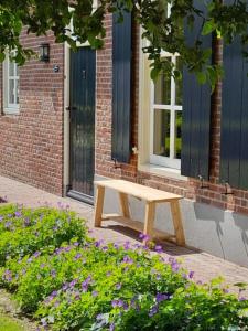 a wooden bench sitting in front of a building at Onder De Wolfskap bed en ontbijt in Haaren