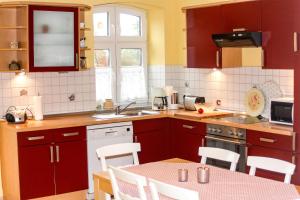 a kitchen with red cabinets and a table with chairs at Im Obsthaus 9 in Göhl