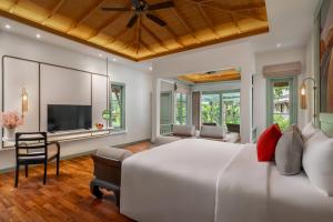 a bedroom with a large white bed and a television at La Solaya Khao Lak in Khao Lak