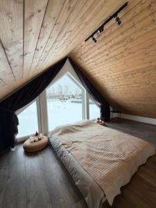 a bedroom with a large bed with a large window at REAL House in Vītoliņi