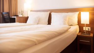 a bed with white sheets and pillows in a hotel room at Bernstein Landhaus Nordhelle in Meinerzhagen