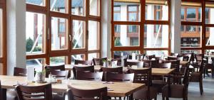 a restaurant with wooden tables and chairs and windows at Bernstein Landhaus Nordhelle in Meinerzhagen +7 photos