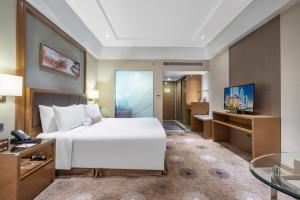 a bedroom with a bed and a desk and a television at Ramada Plaza Pudong Shanghai in Shanghai