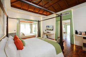 a bedroom with a large white bed with orange and green pillows at La Solaya Khao Lak in Khao Lak +37 photos