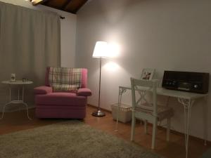 a living room with a pink chair and a table and a lamp at Casa das Castanhas - Cinfães Douro in Cinfães