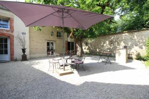 a patio with a table and chairs and an umbrella at Le P'tit Clos in Vantoux