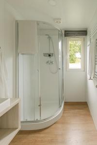 a white bathroom with a shower and a sink at Storkesøen Ribe Holiday Cottages and Apartments in Ribe +89 photos