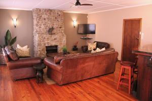 a living room with a brown leather couch and a fireplace at The Ranch House at African Safari Lodge in Grahamstown