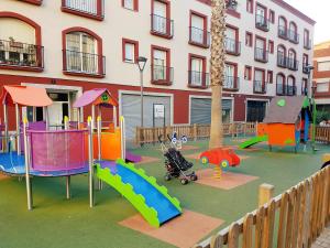 un parque infantil con diferentes tipos de equipos de juego frente a un edificio en Manuela Beach City, en Lloret de Mar