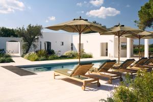 a group of chairs and umbrellas next to a pool at Masseria Pietra e Terra in Carovigno